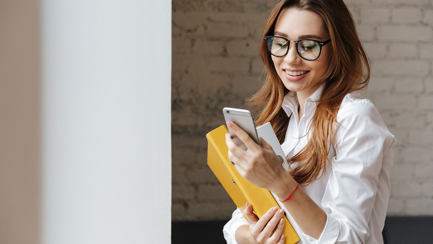 happy-business-woman-indoors-using-mobile-phone-P9WS3SD