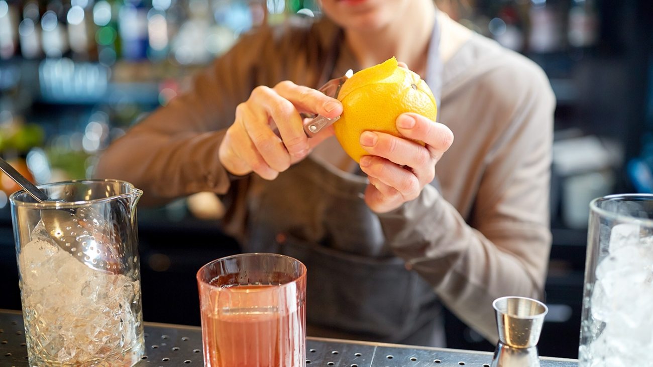 bartender-peels-orange-peel-for-cocktail-at-bar-P97775Y