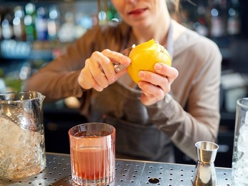 bartender-peels-orange-peel-for-cocktail-at-bar-P97775Y