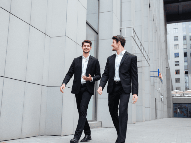 two-businessmen-walking-and-talking-in-the-city-PMW8E26