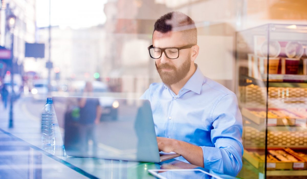 Hipster-manager-in-cafe,-working-on-laptop-by-window