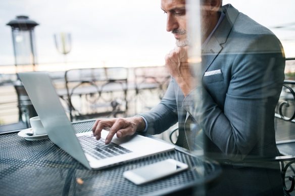 Mature-businessman-with-laptop-outside-a-cafe.