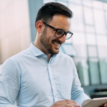 portrait-of-businessman-in-glasses-holding-tablet-AWVHCJU