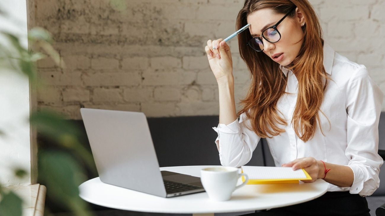 thoughtful-business-woman-indoors-using-laptop-P5HYUQX