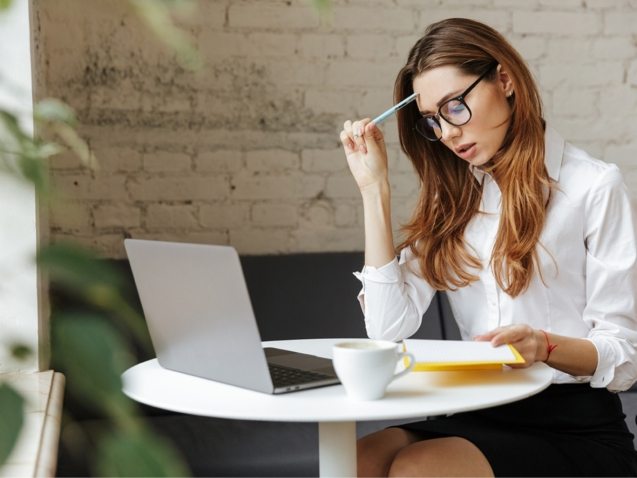 thoughtful-business-woman-indoors-using-laptop-P5HYUQX