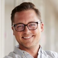 portrait-of-smiling-male-school-teacher-standing-7KLZDMS