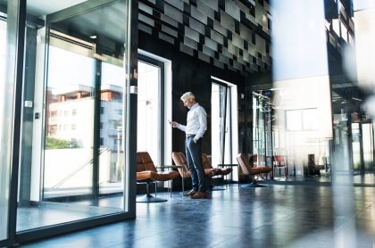 Mature-businessman-with-smartphone-in-the-office.