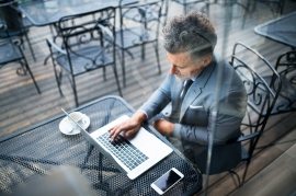 mature-businessman-with-laptop-outside-a-cafe-PXAVBAC