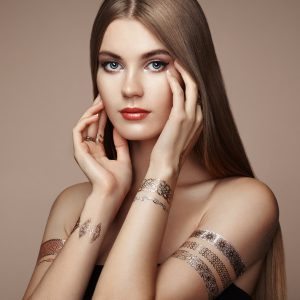 Fashion portrait of elegant woman with magnificent hair. Blonde girl. Perfect make-up. Girl in elegant dress. Flash tattoo gold