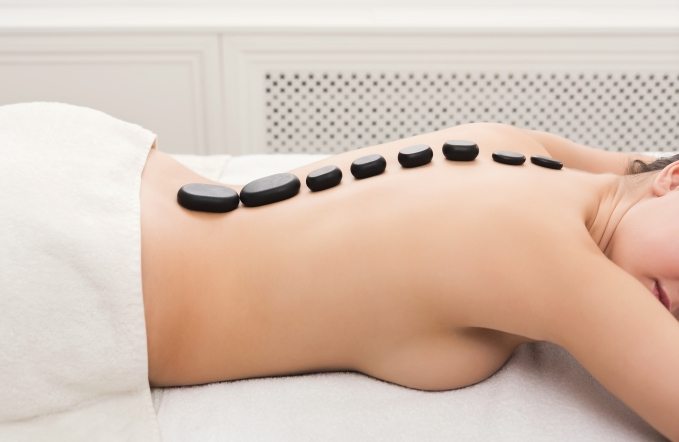 Beautiful woman at hot stones massage in spa salon. Beauty treatment therapy, wellness and relaxation concept, closeup, side view