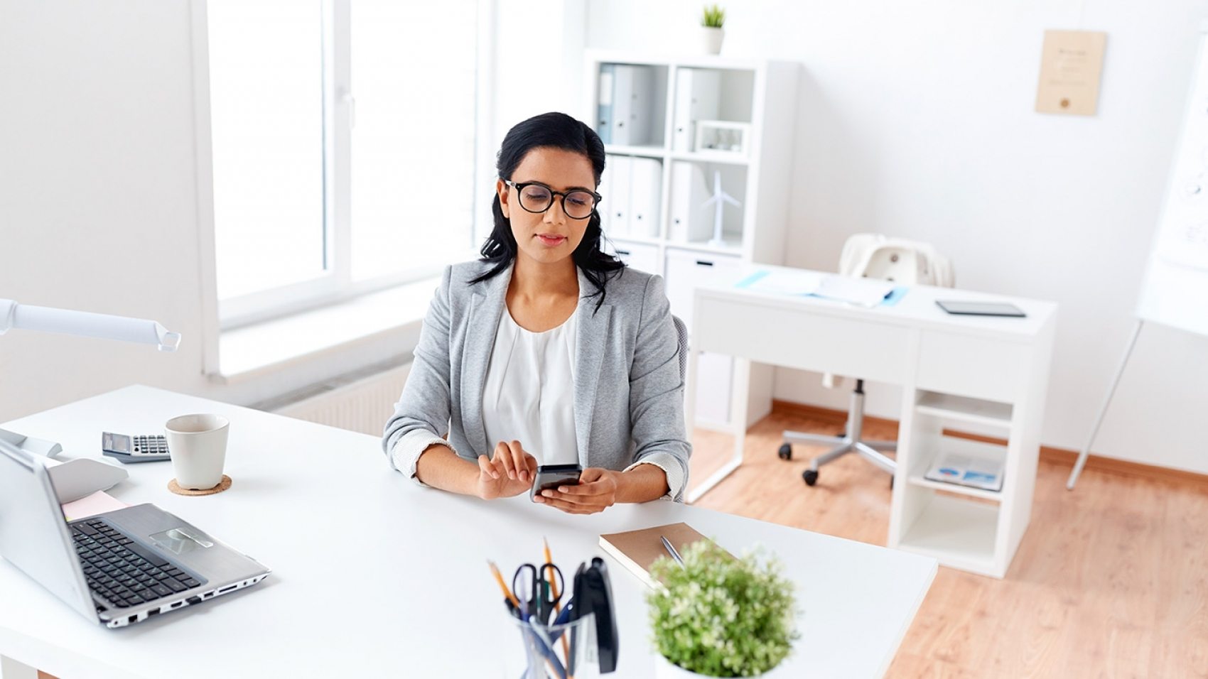 businesswoman-messaging-on-smartphone-at-office-P5AQU8Y