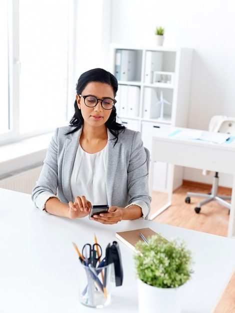 businesswoman-messaging-on-smartphone-at-office-P5AQU8Y
