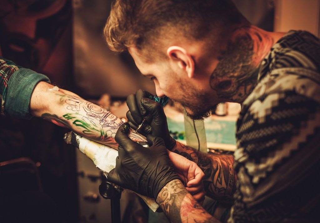 Tattoo artist makes a tattoo on a man's hand